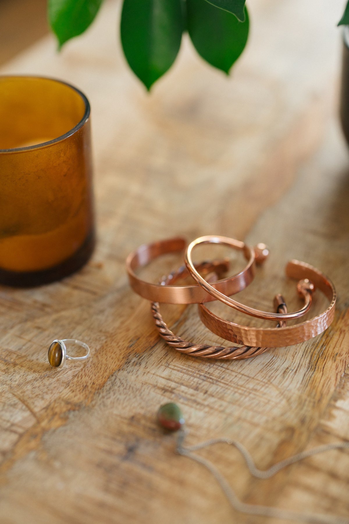 Kopero Koppararmband, alla fyra varianterna tillsammans på ett träbord med ett ljus och en ring