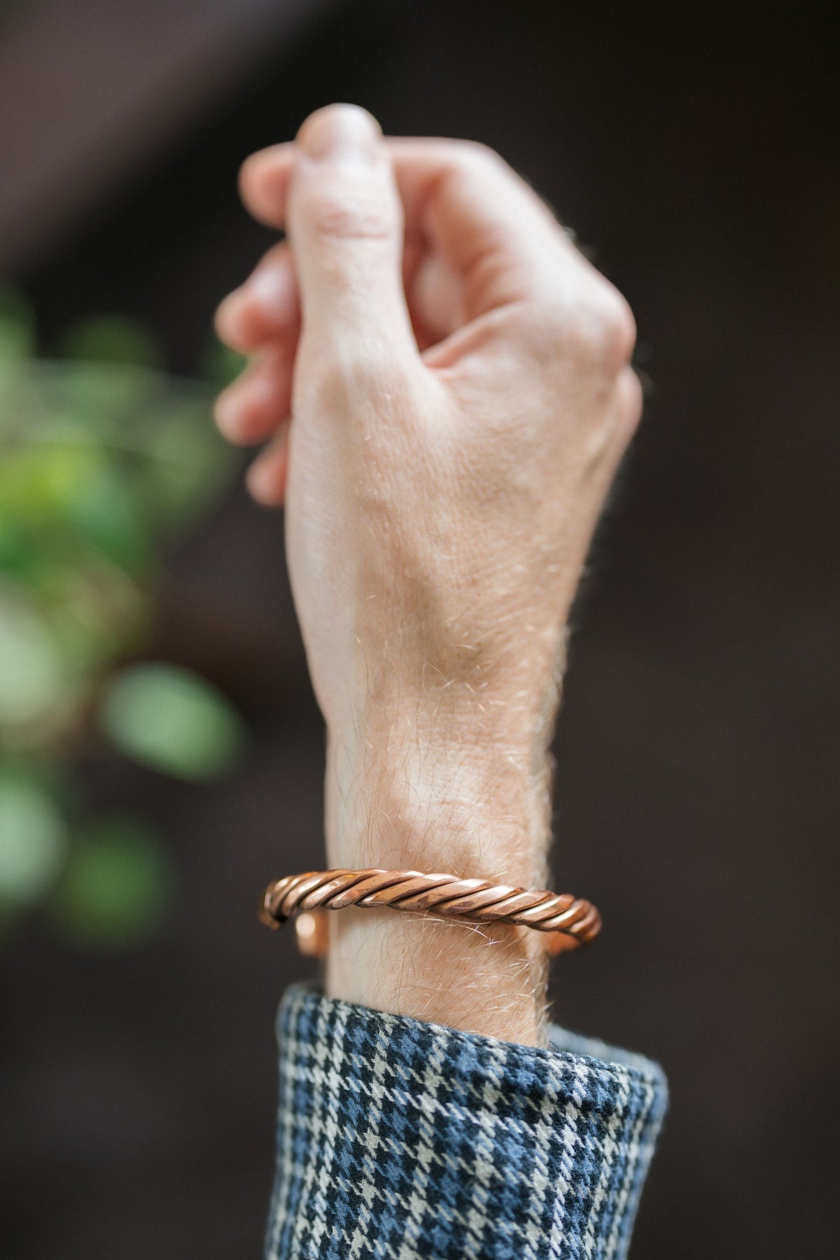 Kopero Koppararmband Tvinnat, på handleden, med handen uppåt mot en mörk bakgrund