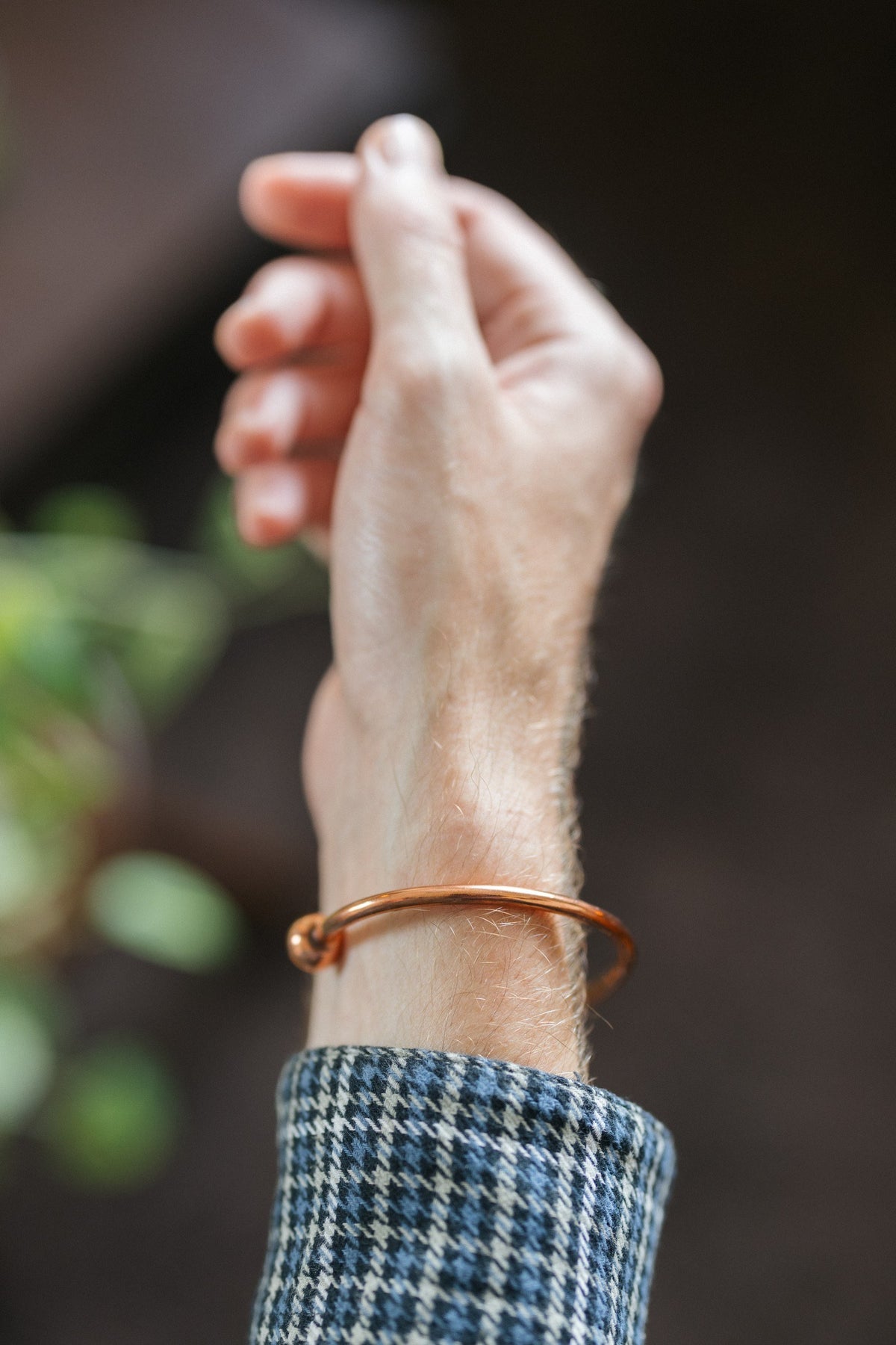 Kopero Koppararmband Runt, på handleden, med handen uppåt mot en mörk bakgrund