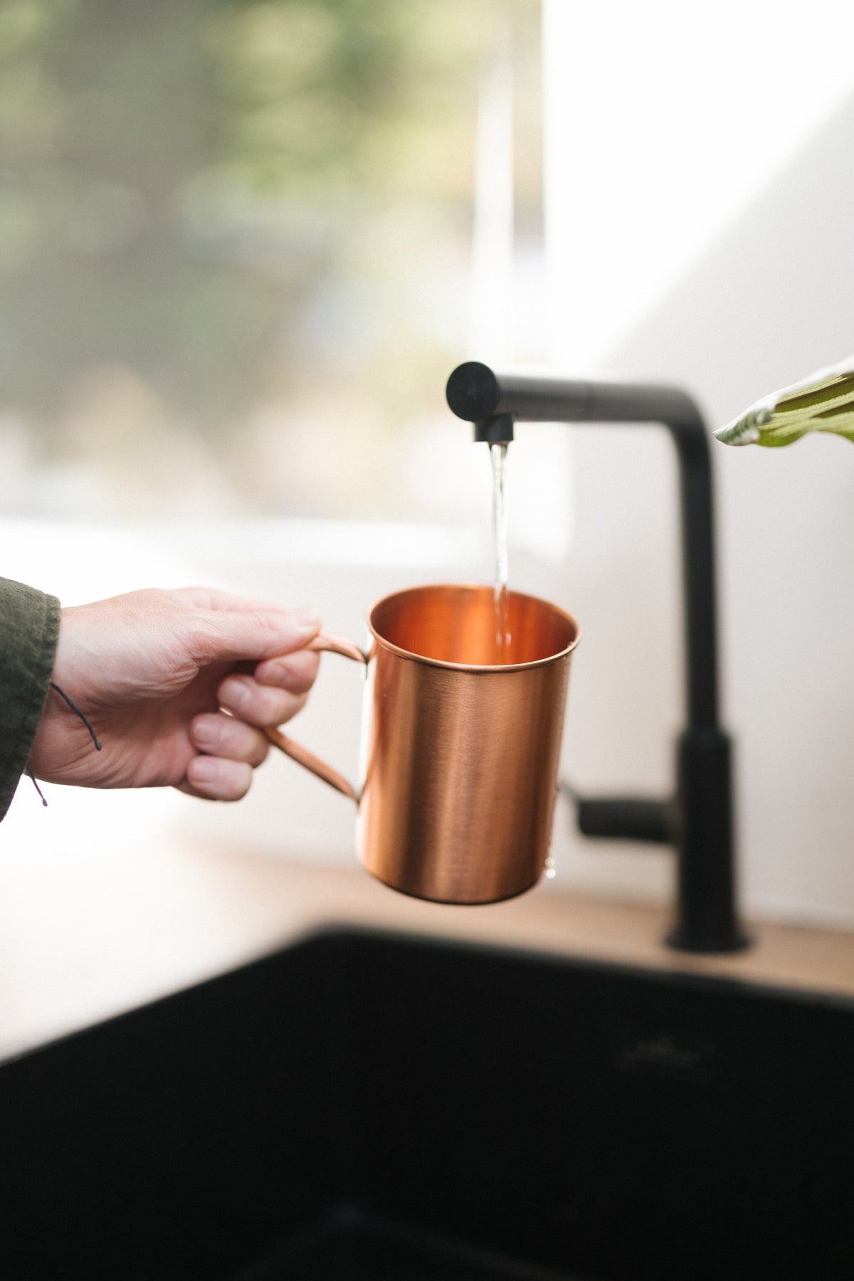 Kopero Kopparmugg Slät, i en hand under kranen