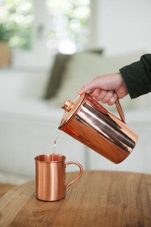 Kopero Kopparmugg Slät, medan vatten hälls i från en kopparkanna