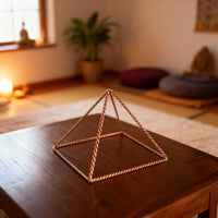 Kopero Kopparpyramid Energizer Tvinnad Liten (14,56 cm) på ett soffbord i ett meditationsrum