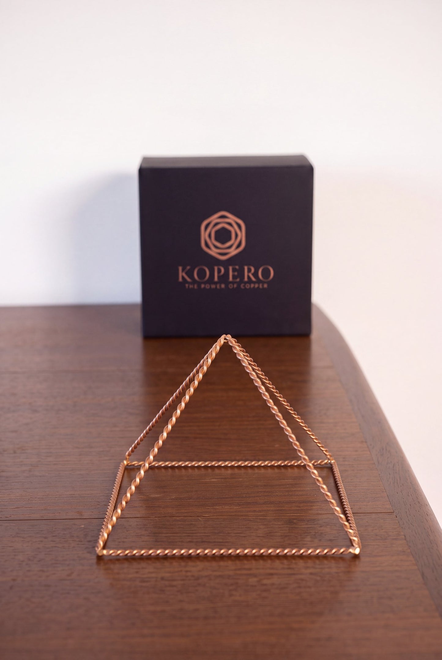 Kopero Kopparpyramid Energizer Tvinnad Liten (14,56 cm) framför den svarta Kopero-presentasken