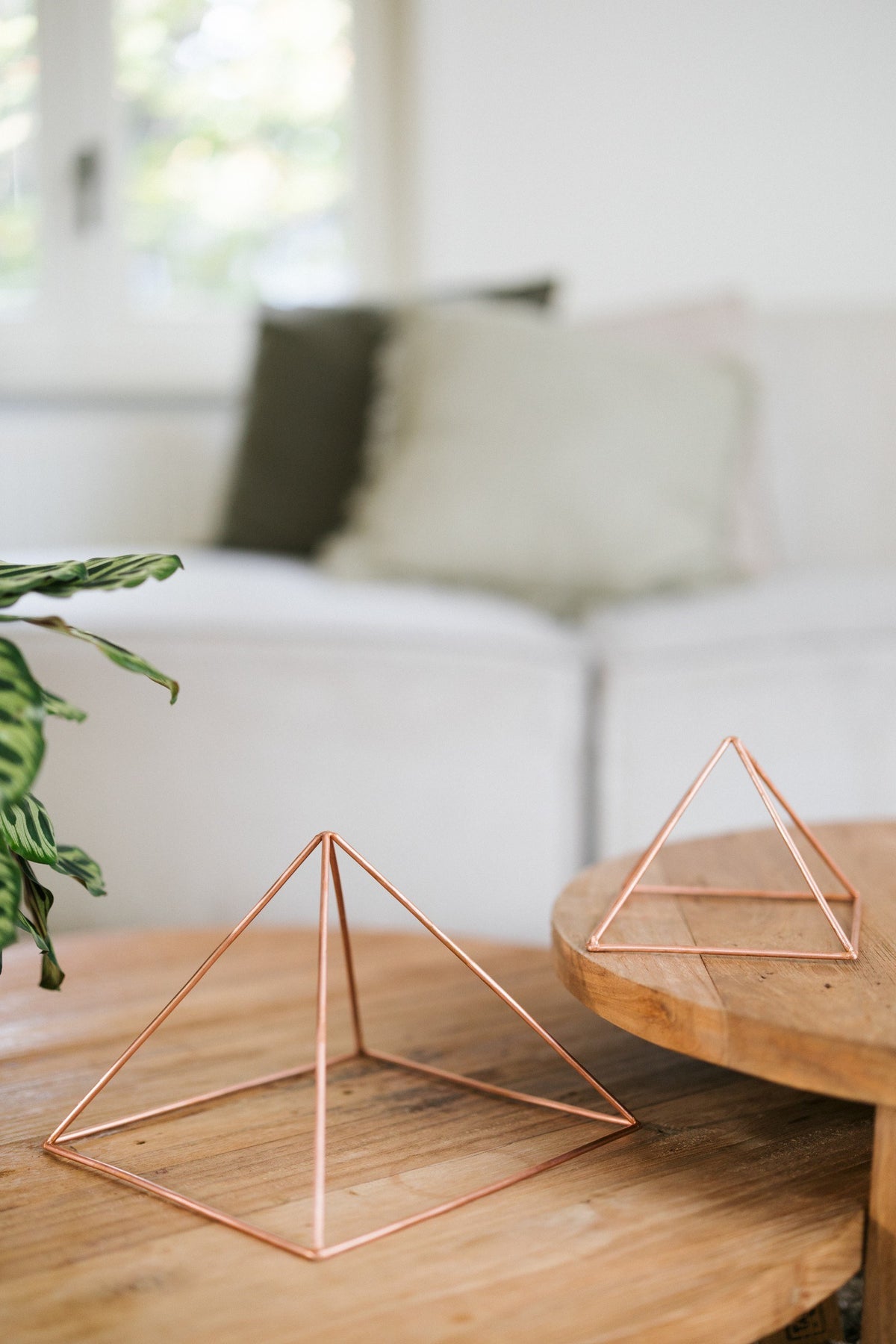 Kopero Kopparpyramid Energizer Slät, den lilla och den stora pyramiden bredvid varandra på två träbord