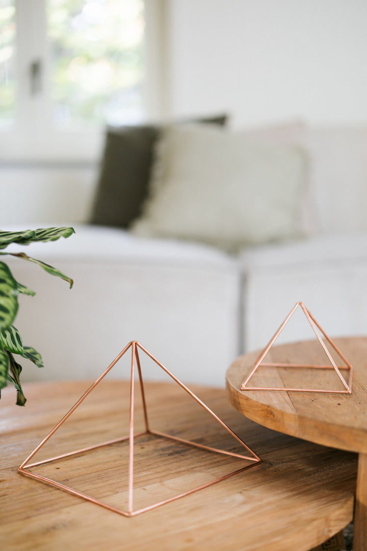 Kopero Kopparpyramid Energizer Slät, den lilla och den stora pyramiden bredvid varandra på två träbord