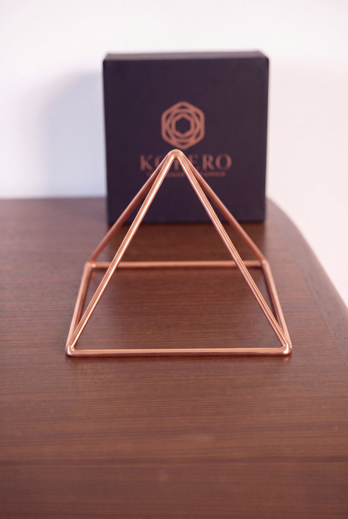 Kopero Kopparpyramid Energizer Slät Liten (14,56 cm) framför den svarta Kopero-presentasken