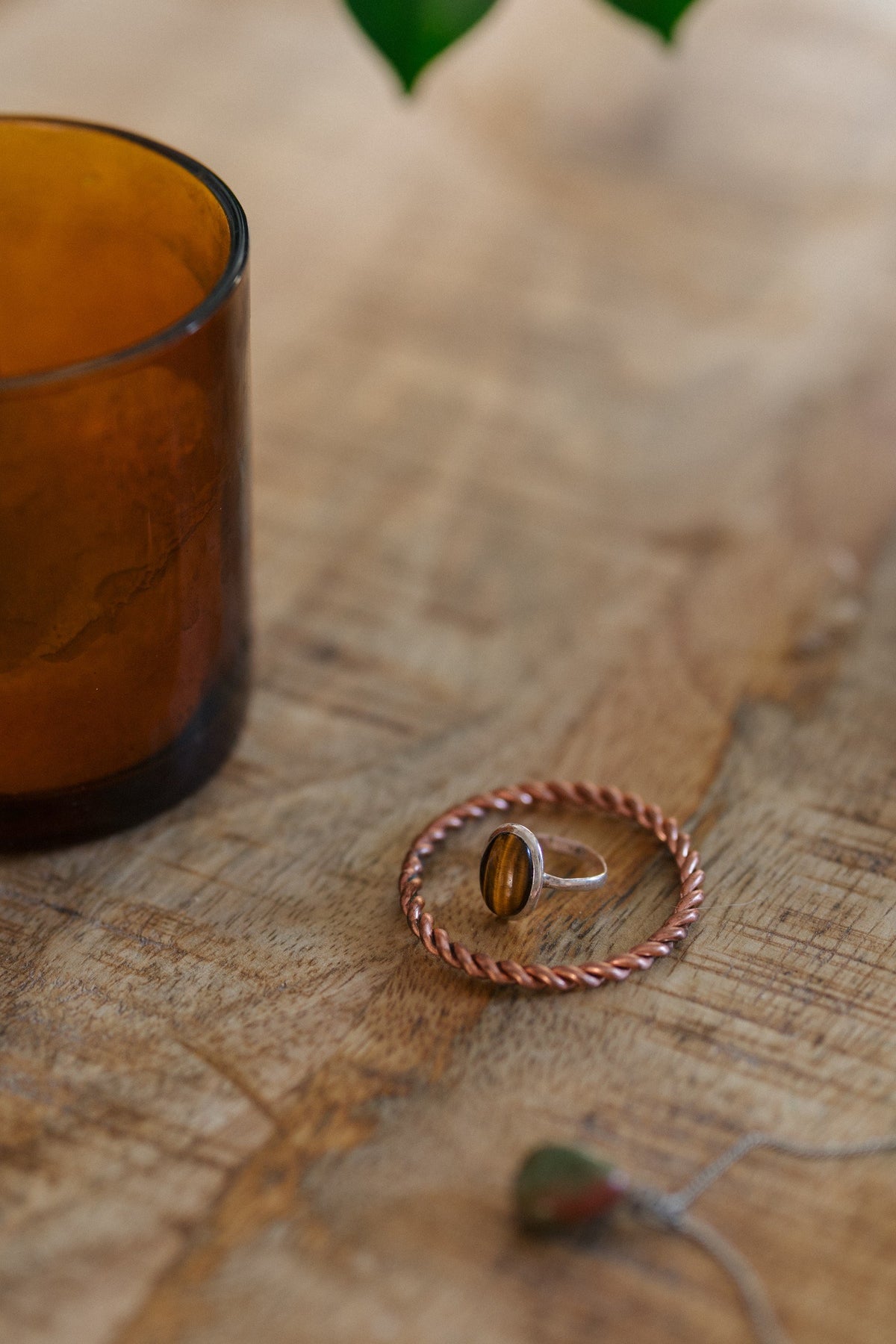 Kopero Koppartensorring, på ett träbord med en ring med tigeröga och en ljushållare i glas