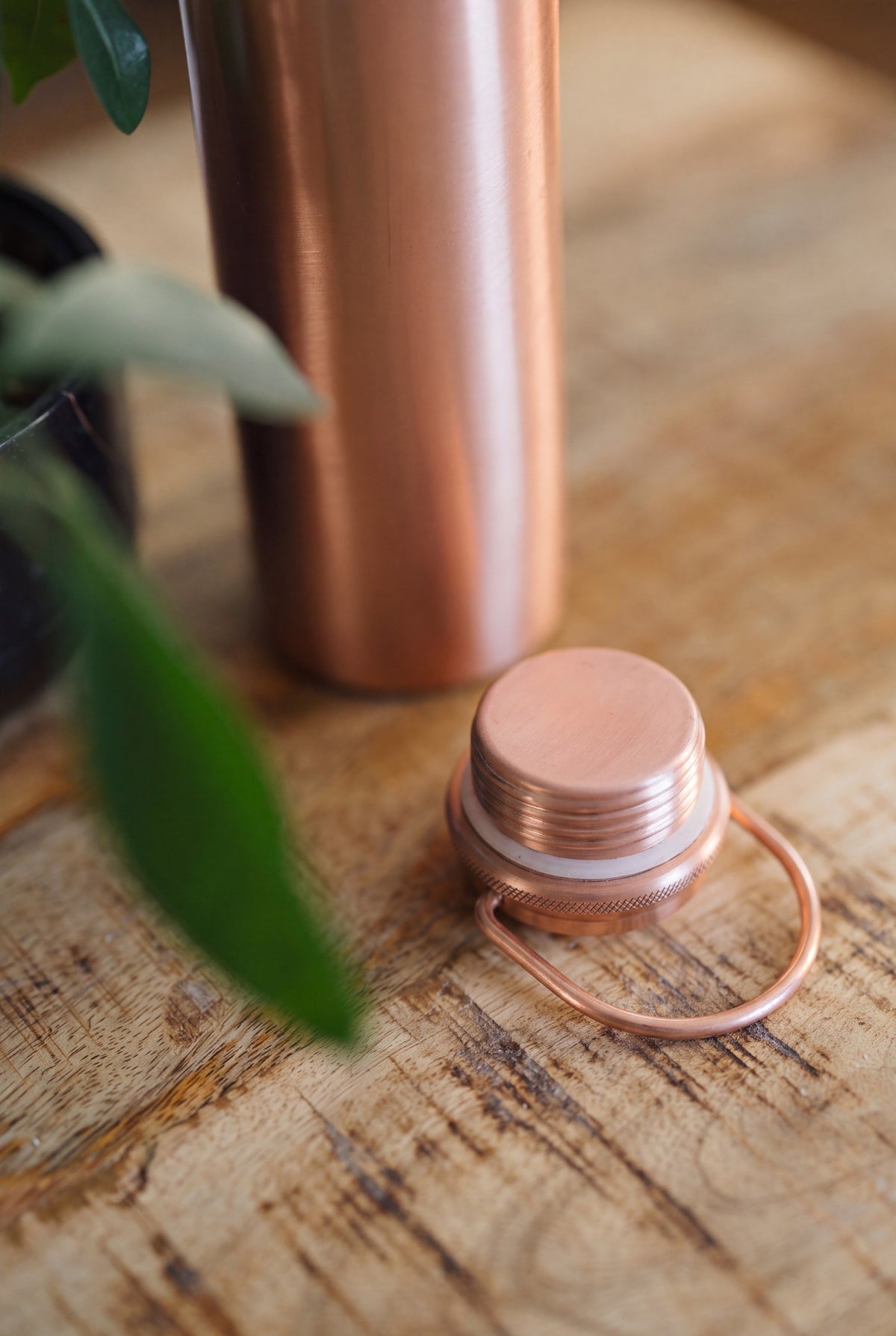 Kopero Kopparvattenflaska Slät, närbild av det lösa locket med vridhandtag på ett träbord